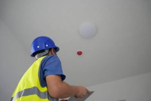 The engineer checks the smoke alarm with a tablet The engineer checks the smoke alarm with a tablet